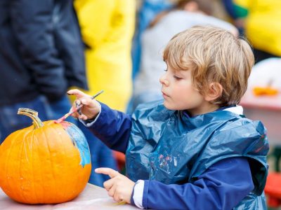 Little boy painting a pumpkin.